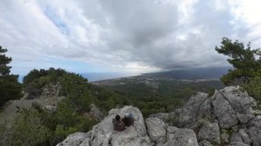 Uçsuz bucaksız deniz manzarasını ve Geniş Açı Perspektifli Bulutlu Gökyüzünün Altında Uzak Şehir 'i izleyen bir çift.