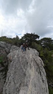 Dikey video. 360 derecelik Küresel Panorama 'da Deniz ve Dağların Altında Bulutlu Gökyüzü Altında Oturan Bir Çift