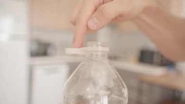 Plastik bir şişeye el ile açılamayan kapağı bastırmak, Plastik atıkları azaltmak için çevre dostu bir çözümü ön plana çıkarmak, yakın çekim...