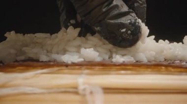 Düşük açılı Makro Bir Eldiven Çekimi Siyah Eldivenli Yapışkan Suşi Pilavı Bir Norveç çarşafına basıyor Kamera Bambu Mat boyunca ileri doğru kayıyor