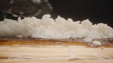 Siyah Eldiven Giyen Bir Elin Makro Yakın Çekimi Nori Çarşafı Üzerindeki Suşi Pirincini Eşit Dağıtırken, Kamera Bambu Çukuru boyunca Hareket Ederken, Süreci Vurguluyor