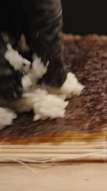 Dikey video. Siyah Eldivenli, Yapışkan Suşi Pilavlı, Nori çarşaflı, Bambu Mat, Yakın Çekim Vurgulama Dokusu ve Detaylı