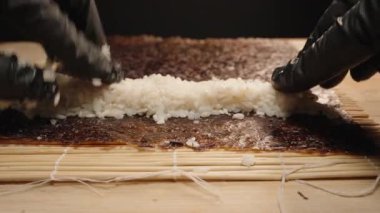 Siyah Eldivenli, Bambu Mat 'li Suşi Yuvarlayan Nori ve Rice' ı Suşi Yapım Sürecinin Yakın Çekiminde Birleştiren