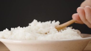 Tahta bir kaşıkla el ele tutuşmak Buharda pişen beyaz pirinci kaseden çıkarmak, Nemli Tanelerle Isıyı ve Yumuşak dokuyu yakalamak