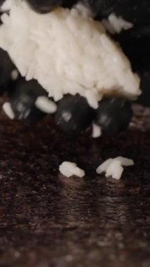 Dikey video. Siyah Eldivenli Yapışkan Beyaz Pilavı, Nori Çarşafı üzerine sıkıca bastırarak Suşi 'nin Hassas ve Teknikli Yuvarlanmasını Sağlama Aldı