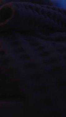 Dikey video. Mavi Ortam Işıklandırması, Ön Düşük Açı, Ekran Bağımlılığı Konseptiyle Gece Yatağında Yatarken İki Elinle Akıllı Telefonu Tutan Kadın