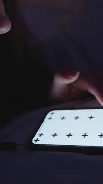 Dikey video. Tek Elli Kafalı Kadın Akıllı Telefonu Küçük Aydınlık Yatak Odası 'nda İzleme İşaretleri ile Kaydırırken, Kapalı Düşük Açı, Gece Alışkanlığı Konsepti