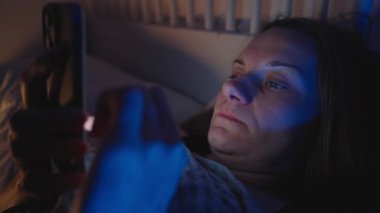Yataktaki Yorgun Kadın Akıllı Telefonu Sıyırdı ve Gözleri İki Elle ovuşturdu Gece Sosyal Beslemeden Sonra, Mavi Ortam Işığıyla Yan Açı, Ekran Yorgunluğu Konsepti