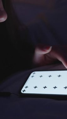 Dikey video. Tek Elli Kafalı Kadın Akıllı Telefonu Küçük Aydınlık Yatak Odası 'nda İzleme İşaretleri ile Kaydırırken, Kapalı Düşük Açı, Gece Alışkanlığı Konsepti