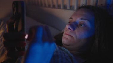 Yataktaki Yorgun Kadın Akıllı Telefonu Sıyırdı ve Gözleri İki Elle ovuşturdu Gece Sosyal Beslemeden Sonra, Mavi Ortam Işığıyla Yan Açı, Ekran Yorgunluğu Konsepti