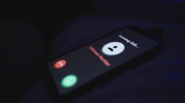 Bilinmeyen Numara 'dan gelen arama, Smartphone Screen' de Mavi Işık, Yakın Çekim Açısı, Gece Karmaşası Konsepti ile Yatakta Dinleniyor