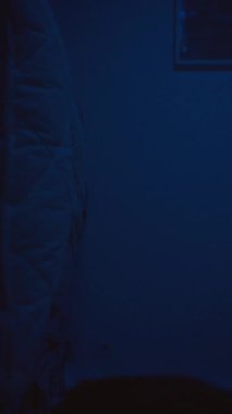 Dikey video. Genç Kadın Yastığa Düşüyor ve Bir Mesaj Yazmaya Başlıyor, Mesajı Gönderiyor ve Telefonu Beklentiyle Göğse Kucaklıyor, Yüzeyin Sığ Derinliği ve Romantik İletişim Konseptiyle Yan Açı 'dan Yakalandı