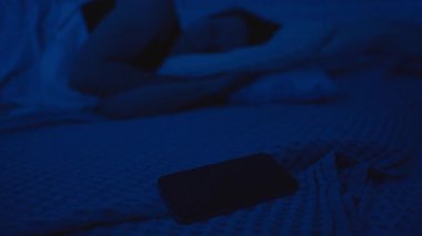 Gece Yatağında Yatan Kadın Telefonuna Uzanıyor ve Sahtekarlık, Düşük Işık Sahnesi, Ekrana Yakın Odaklı, Dijital Güvenlik Konseptine Odaklanan Çağrıyı Reddediyor