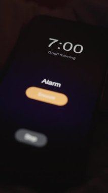 Dikey video. Yastıklı Yalnız Kadın Yüzü Örtüyor ve Karanlık Oda 'da Sabah 7 Alarmını Kapatmak için Akıllı Telefona Ulaşır, Düşük Açılı Kapalı, İsteksiz Uyandırma Konsepti