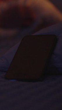 Dikey video. Kadın Yastığı Sabah 6: 00 'da Çalan Akıllı Telefon Alarmı' na doğru attı Karanlıkta Yatakta Yatarken, Yakın-Yakın-Alçak Açı, Hüsrana uğramış Uyandırma Konsepti