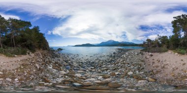 Türkiye 'nin Phaselis kentindeki Rocky Shoreline' in pürüzsüz 360 derecelik Panorama 'sı, Sakin Mavi Denizi, Uzak Dağları ve Bereketli Yeşil Kıyı Sükuneti ve Doğa Kaçışı Konseptiyle çevrili Bulutlu Gökyüzü