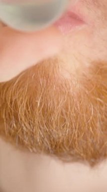 Dikey video. Sakallı Bir Adamın Ağız Bakımı İçin Küçük Şeffaf Bir Bardaktan Yeşil Sıvı İçmesi Ağız Suyu Sakız ve Diş Tedavisi İçin Kullanımı