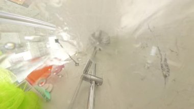 Dikey video. Modern Banyo 'daki Duş başlığından fışkıran su Mermer Duvarlar ve Renkli Banyo Malzemeleri Görünür, Alt Hijyen ve Duş rutininden Yakından Yakından Çekilmiş