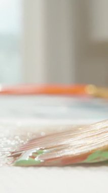 Dikey video. Boyalı Fırça Çok Renkli Boyayı Kapalı Görünümde Dolly Kaydırma Hareketi ve Dikenli Yeşil Kırmızı ve Turuncu, Renk Harmanlama Konsepti