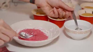 Pembe Dondurmayı Beyaz Kasede Karıştırmak Kaşıkla Fırınlanmış Kap Kekleri Mutfak Tezgahında Kırmızı Tutucuda, Kapalı Görüş, Tatlı Hazırlama Konsepti