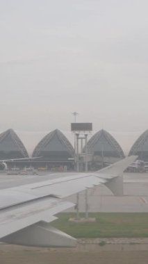 Dikey video. Uçak kalkıştan önce, Modern Mimarlık Konsepti ile Havalimanı Sahnesi, Havalimanı Sahnesi Taksiyolunda Dönerken Uçak Terminal Binaları ve Uçak Penceresinden İzle