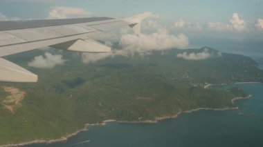 Açık Mavi Gök Bulutları ile kısmen kaplanmış Lush Green Dağları ve Kıyı Kanadı 'ndan Uçan Uçak Kanadı, Manzaralı Ada Üstgeçidi