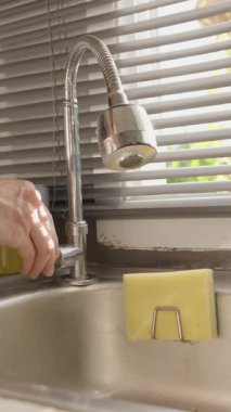 Dikey video. Paslanmaz Çelik Mutfak Lavabosunda Sünger ve Bulaşık, Göz Seviyesi Açısı, Günlük Ev İşleri Konsepti