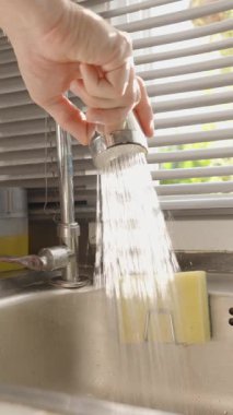 Dikey video. Paslanmaz Çelik Mutfak Lavabosu, Göz Seviyesi Açısı, Ev Akımı Konsepti 'ndeki Pencere Perdeleri Arasında Süzen Güneş Işığı ile El Değiştirme Modu