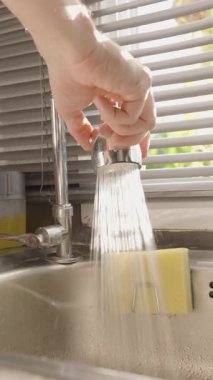 Dikey video. El Tutma Esnek Musluğu Parlak Güneş Işığının altında Jaluziler, Göz Seviyesi Açısı, Mutfak Temizleme Konsepti