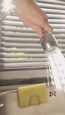 Dikey video. Paslanmaz Çelik Lavabo İçinde Farklı Yönlerde Su Akıntısını Yöneten El Gösterici Esnek Musluk Perdelerle Gün Işığı, Ürün Şovu Konsepti