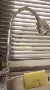 Dikey video. Arka plandaki güneşlikler, Göz Seviyesi Açısı, Su Aracı Konsepti, Su Tedarik Konsepti ve Güneş Işığıyla Su Akışı Gösterilmesin diye Esnek Musluk Musluğu 'na El Tıklatma