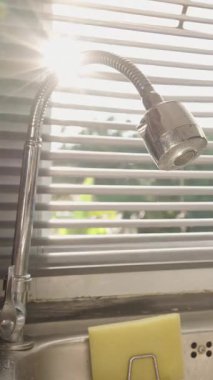 Dikey video. Son Gün Işıkları Esnek Musluğa Yansıtırken Mutfak Penceresinin Kapanması ve Karanlık Yerleşmeden Önce Batması, Göz Seviyesi Açısı, Gece Kavramına Geçiş