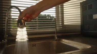 El Tutuşu Esnek Musluk Lavabo 'ya Yoğun Güneş Işığı Perdeleri Arkasında, Göz Seviyesi Çekimi, Temizlik Rutini Konsepti