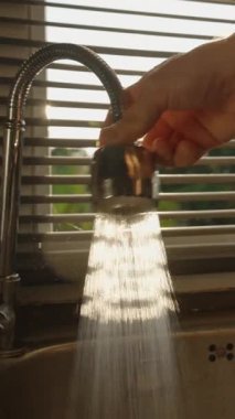 Dikey video. El Tutuşu Esnek Musluk Lavabo 'ya Yoğun Güneş Işığı Perdeleri Arkasında, Göz Seviyesi Çekimi, Temizlik Rutini Konsepti