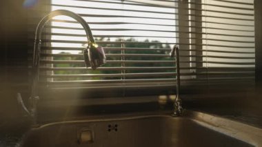 Güneş Işığı Perdelerden Süzülürken Esnek Musluktan Damlayan Su Atık, Göz Seviyesi Açısı, Su Koruması Konseptini Engellemek İçin Sıkıca Kapanıyor