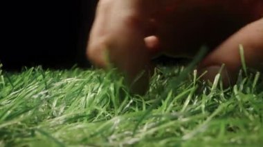 Görünür Doku ve Basınç ile Yapay Yeşil Çimene Bastıran Parmakların Kapanışı Loş Işıklandırma Konsepti Duyusal Geribildirim ve Malzeme Simülasyonunda Dokunsal Etkileşim Oluşturuyor