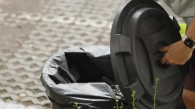 Eldiven Giyen Kadın, Arka Açı, Temizlik Eylemi, Atık Yönetimi Konsepti, Temizleme Eylemi, Atık Yönetimi Konsepti 'nden Arka Alanı Bitkilerle Kapalı Konutta Lid Açık Tutarken Çöp Kutusu' ndan Ölü Kertenkele Çıkardı