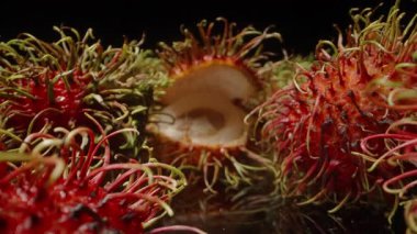 Dolly Kaydırıcı Yakın Çekim Bir Soyulmuş ve Açığa Çıkan Etle Rambutan Meyveleri Arasında ve Yansıtıcı Yüzeyde Diğerleri Arkaplanda