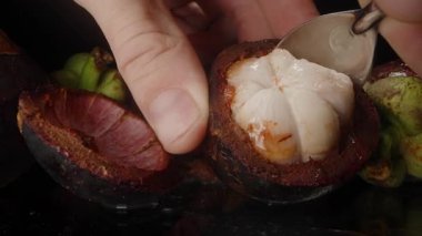 Yarım Deniz Kabuğu 'ndan kaşık Scooping Mangosteen Pulp Elle Yansıtıcı Yüzeye Yakından Meyve Desteği
