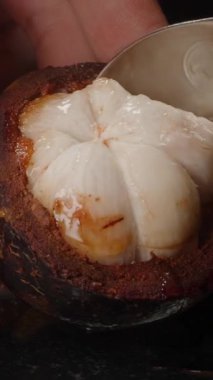 Yarım Deniz Kabuğu 'ndan kaşık Scooping Mangosteen Pulp Elle Yansıtıcı Yüzeye Yakından Meyve Desteği
