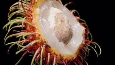 Yarım Rambutan, Sulu Beyaz Etli ve Kırmızı Kıllı Kabukla çevrili Siyah Arkaplanda Makro Yakın plan, Tropikal Meyve Detaylı Konsept