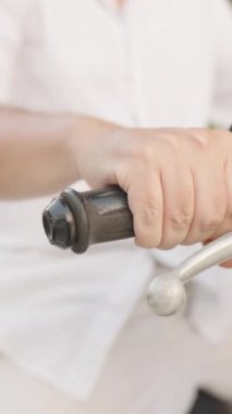 Dikey video. Beyaz gömlek, yan makro görüş, ivme ve motor başlatma kavramı giyerken Erkek Elinin Yakın Çekimi Scooter 'ın Gazına Basma Kavramı