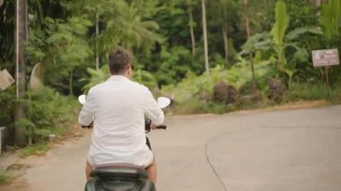 Motosikletli Adam Yoğun Yeşillik, Merkezli Arka Görünüm, Tropikal Keşif Konsepti ve Yoğun Yeşillik Ormanı 'nda Kavisli Yol' a Doğru Sürüyor