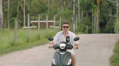 Güneş Gözlüklü Adam 'ın, Tropikal Yeşil Alan' da Scooter sürüşünün, Yavaş Hareket 'te Orman Kuşatılmasının, Huzurlu Seyahat Konseptinin Yakın Çekimi