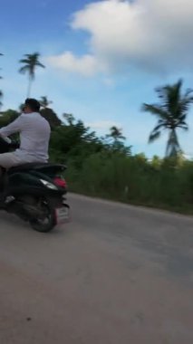 Dikey video. İnsansız Hava Aracı, Scooter Dönüşü Yapan Adamı Palmiye Ağaçları, Hareket Eden Hava Çekimi, Tropikal Chase Konsepti ile İzlemeye Başladı