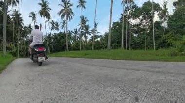 Virajlı Tropikal Yol 'da Scooter Uzağında Sürücü, Lush Vegetation, Düşük Açı İzleme Çekimi Yer Seviyesinden, Olay Yeri İnceleme Konsepti