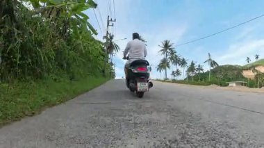 Scooter 'lı Adam Karışık Yüzey Yolu' nda Elektrik Hatları ve Tropikal Ağaçlar, Yer Seviyesi İzleme Çekimi, Ada Yolculuğu Konsepti