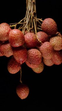 Dikey video. Olgun Lychees Kümesi Kara Arkaplan Karşısında Yavaşça Dönüyor Yakın Çekim ve Düşük Anahtar Vurgulama Doku ve Doğal Yüzey Vurgusu