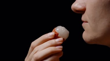 Yüzünün yanında Soyulmuş Lychee 'i tutan Kadın Yumuşak Aydınlatma Altında Yeme ve Siyah Arkaplana Karşı Yakın Bakış