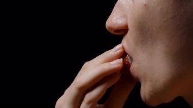 Görünür dişleri ve dudakları ile Soyulmuş Lychee 'yi Isıran Kadın Yumuşak Işığın Altında Karanlık Bir Arkaplanda Doku ve Tazelik Gösteriyor